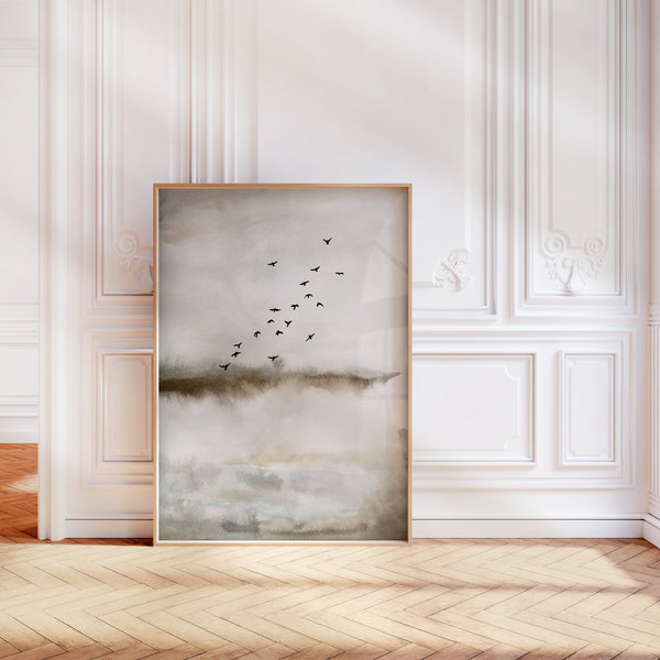 A watercolor painting evoking a sense of freedom and serenity. A flock of birds is depicted in flight against a backdrop of a misty landscape, conveying a feeling of boundless space and peaceful movement. The painting is in front of a white wall.