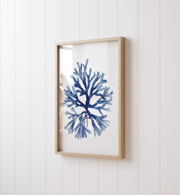 A watercolor painting of a minimalist coral design in deep navy blue adds a touch of nature to a room with white paneling and a white wall.