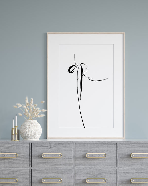 A drawing of plant, rendered in sleek black lines against a crisp white background. The painting is hung on a blue wall, above cupboards. 