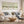 A styled living room featuring a three-panel framed wall art set with soft sage green and beige Japandi abstract landscape designs, hung above a white sofa with gray and blue patterned pillows.