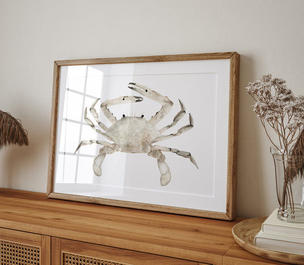 A large, framed watercolor painting of a realistic crab in soft, earthy brown tones hangs on a wall above a wooden sideboard. The painting adds a touch of coastal charm and natural beauty to the space.