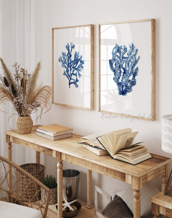 Nautical-themed decor with blue coral prints, books, and dried plants on a wooden table.