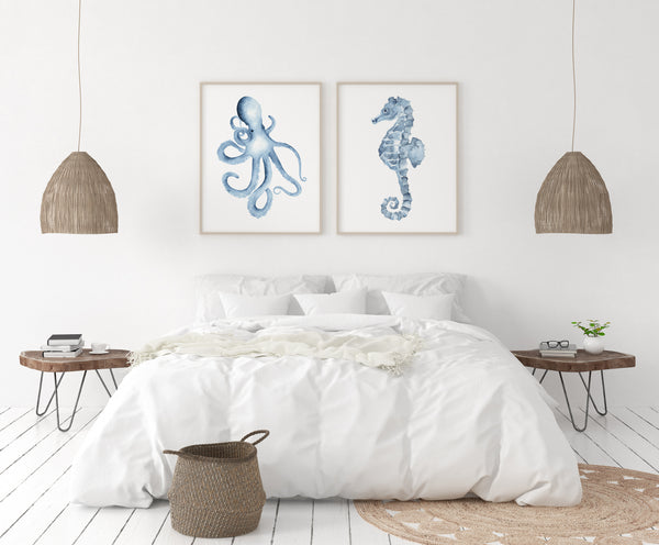 Set of 2 octopus and seahorse wall art prints in wooden frames – coastal watercolor sea life artwork styled above bed in minimalist white bedroom with natural accents