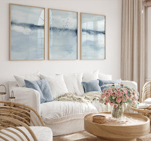 Light blue abstract seascape prints above a white sofa