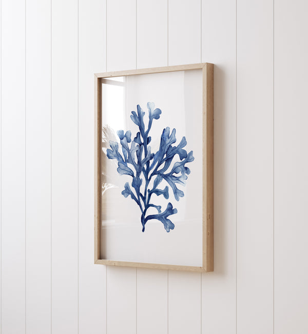 A watercolor painting of a minimalist seaweed design in deep navy blue adds a touch of nature to a room with white paneling and a white wall.