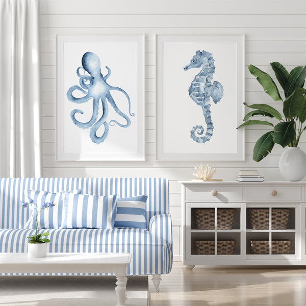 Set of 2 octopus and seahorse wall art prints in white frames – coastal watercolor sea life artwork styled above blue and white striped sofa in bright nautical living room