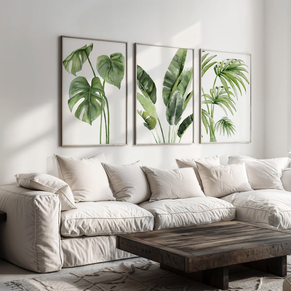 set of 3 frames showing tropical leaves hangs above large couch