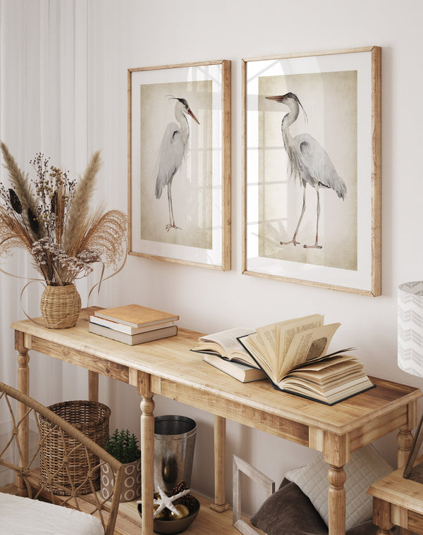 A set of  wooden frames with great blue herons painted on vintage background hang above wooden console table.