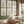 A gallery wall of six botanical illustrations showcasing various wildflowers in black ink on a vintage-inspired tan background. The artwork is displayed in a living room setting with a plush sofa and natural light.