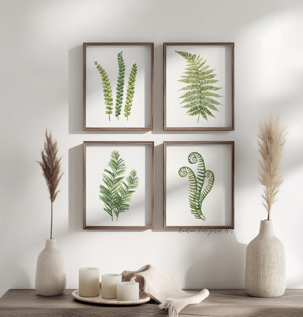 Framed botanical prints skowing minimalist fern leaves in green color on a wall with decorative vases and candles on a table.
