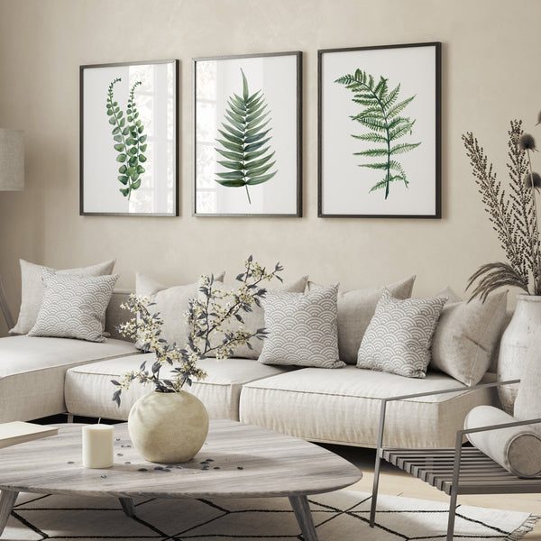 set of 3 black frames with green fern blätter hangs above graue sofa in modern living room decorated in neutral colors