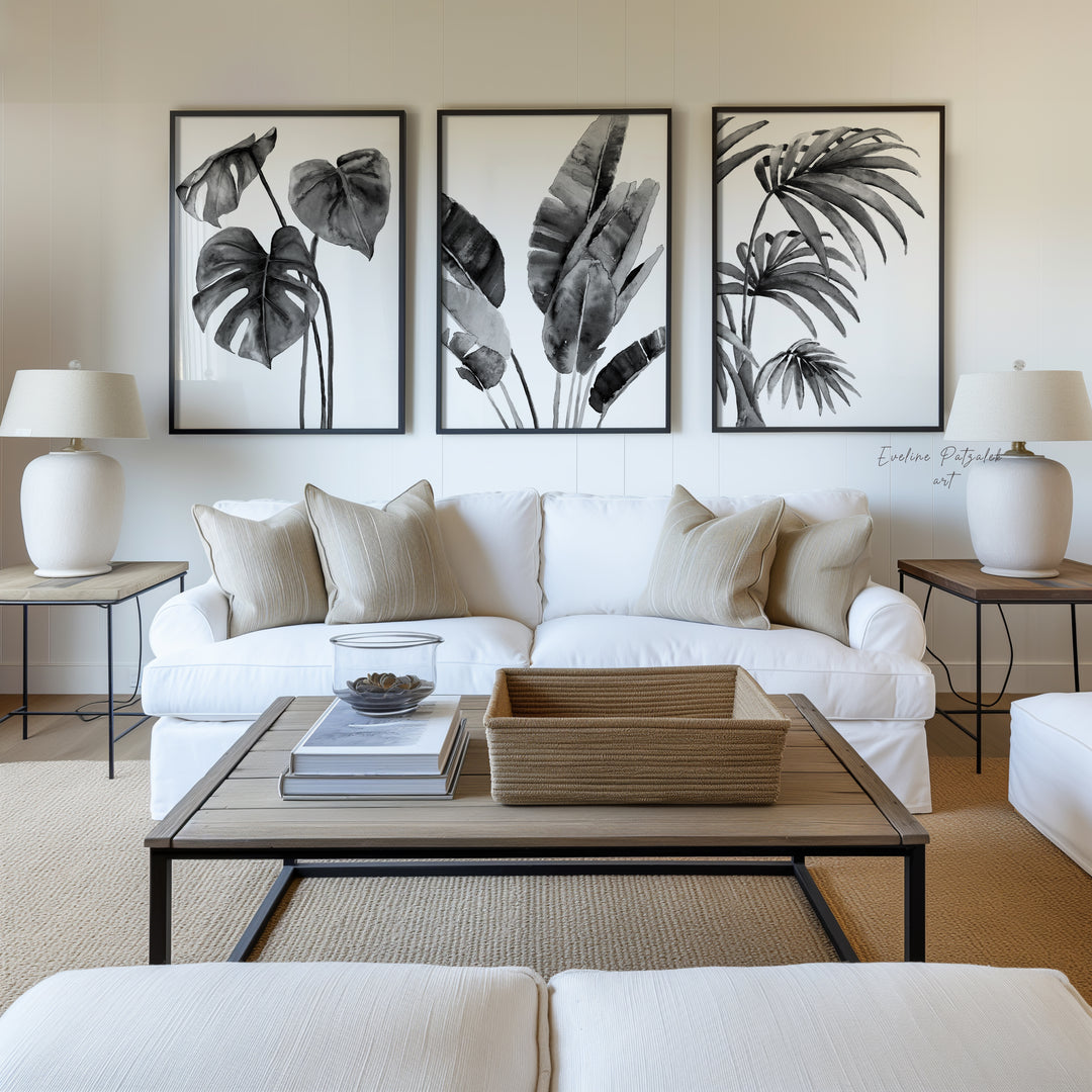 Large black and white botanical wall art set with monstera, banana leaf and palm prints above white sofa in modern Scandinavian living room