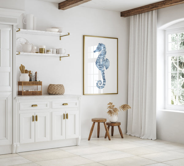 Seahorse watercolor print in a thin gold frame in a white kitchen with open shelves