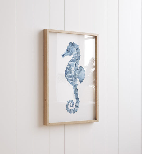 Close-up of the blue watercolor seahorse print in an oak frame on a white panelled wall