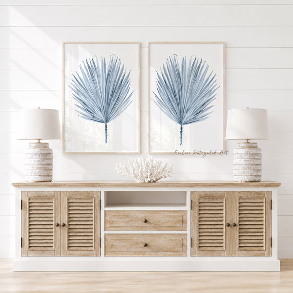 Wooden console table with decorative items and framed blue palm leaves artwork on a white wall.