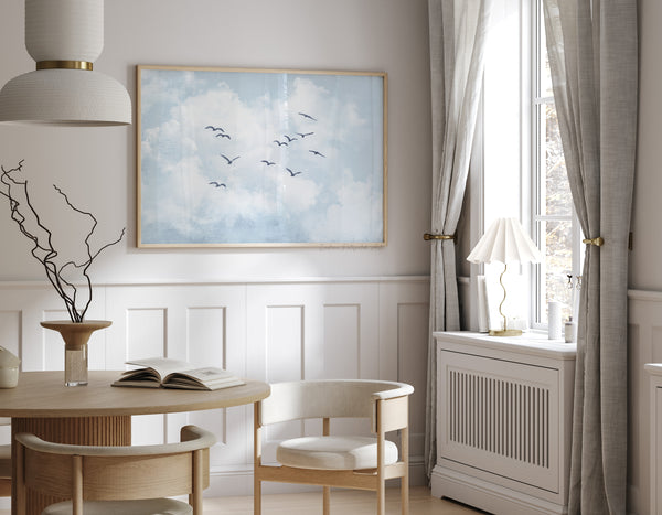 Modern interior design with a table, chairs, and a painting of birds in a blue sky.
