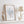 Light blue watercolor coral print in a wooden frame on a white shelf beside a driftwood lamp