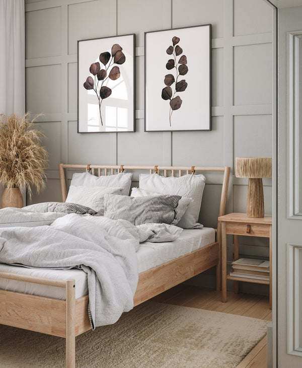 Two brown eucalyptus prints above a wooden bed in a calm Scandinavian bedroom