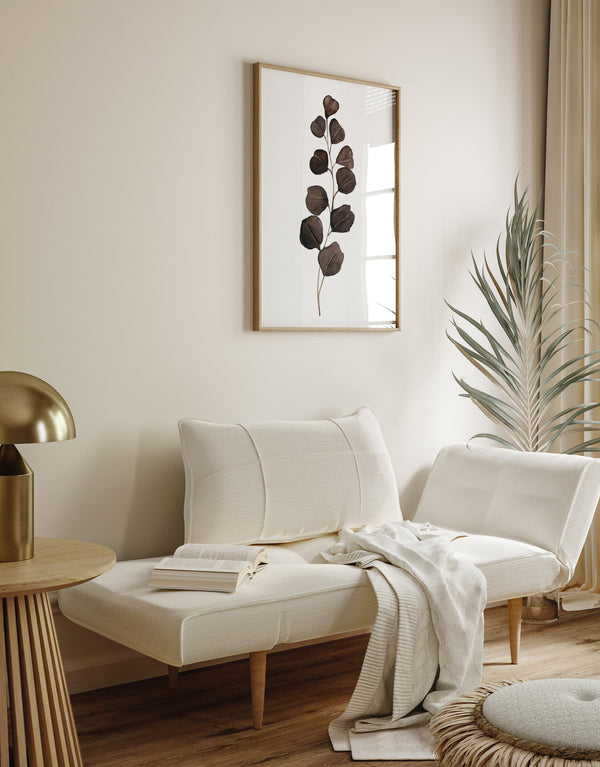 Single deep brown eucalyptus watercolor print above a cream sofa