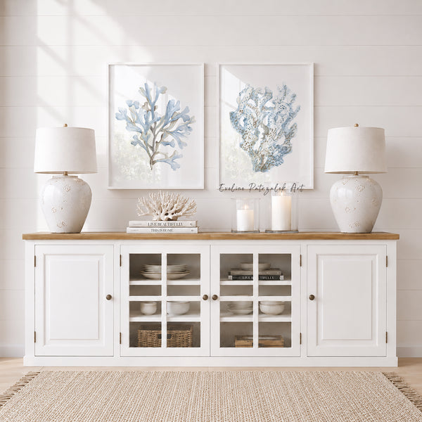 White sideboard with glass doors, two lamps, and light blue coral art in a room with light wood flooring.