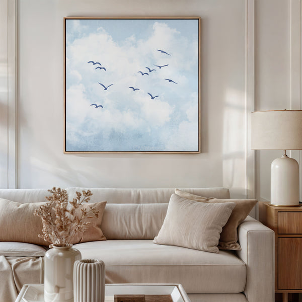 Living room with a beige sofa, decorative pillows, and a framed artwork of birds in the sky.