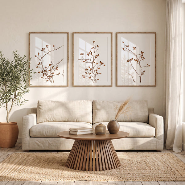 Set of 3 minimalist brown branch prints in oak frames above a linen sofa and jute rug