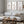 Three brown botanical prints above a grey sofa and rustic wooden coffee table