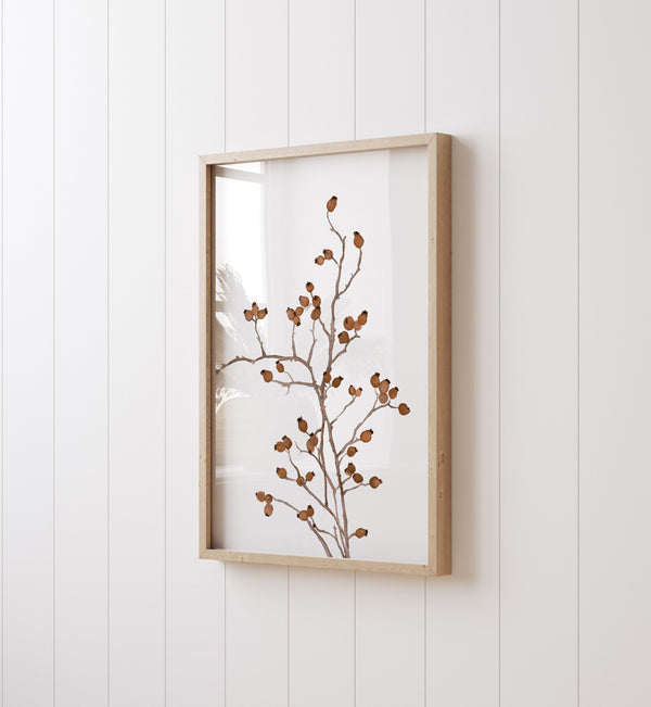 Close-up of a cognac berry branch print in an oak frame on a white wall