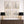Decorative wall art with floral prints above a wooden console table with lamps.