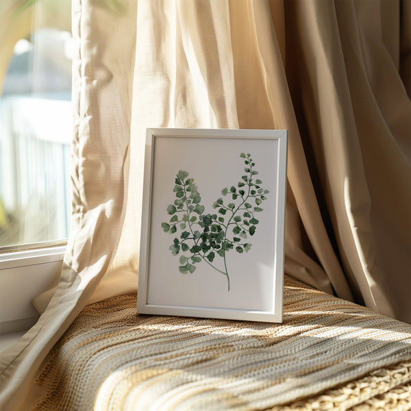 A framed watercolor painting showcases the intricate details of a green fern, resting on a windowsill bathed in sunlight and framed by sheer curtains.