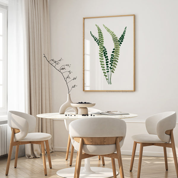 A framed watercolor painting showcases the intricate details of a fern, its small, soft green leaves rendered in subtle hues, creating a calming and elegant atmosphere in a dining room with a round table and upholstered chairs.