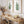 Two green watercolor prints of palm fronds and a fern above a wooden console with dried flowers