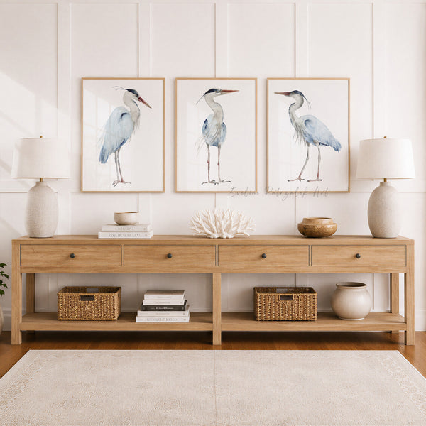 Wooden console table with decorative items and framed artwork of watercolor minimalist heron birds on a white wall.