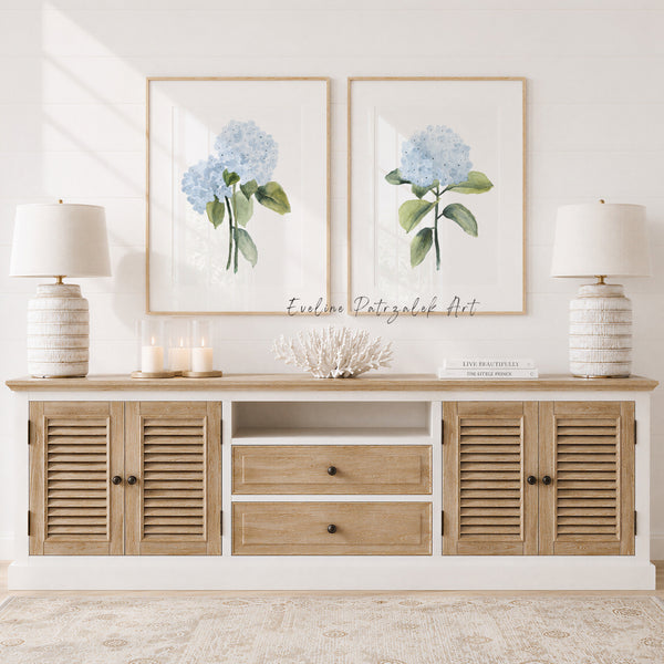 Wooden console table with floral artwork showing minimalist blue hydrangea flowers and decorative items in a bright room.
