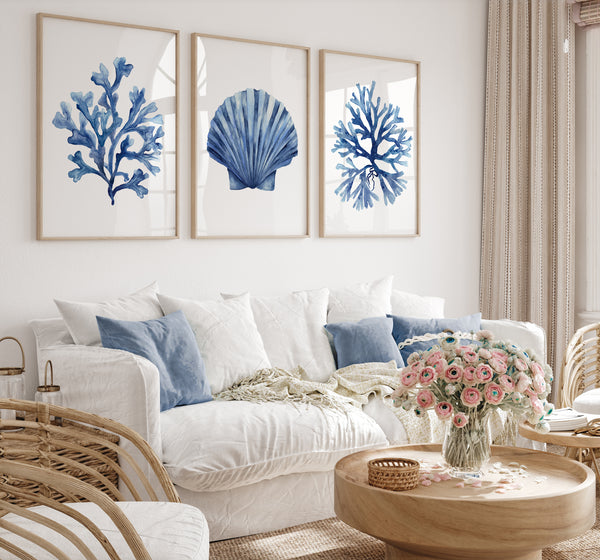 Living room with white sofa, blue pillows, and framed blue coral and shell art on the wall.