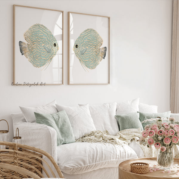Two light green watercolor discus fish prints facing each other above a white linen sofa with mint cushions