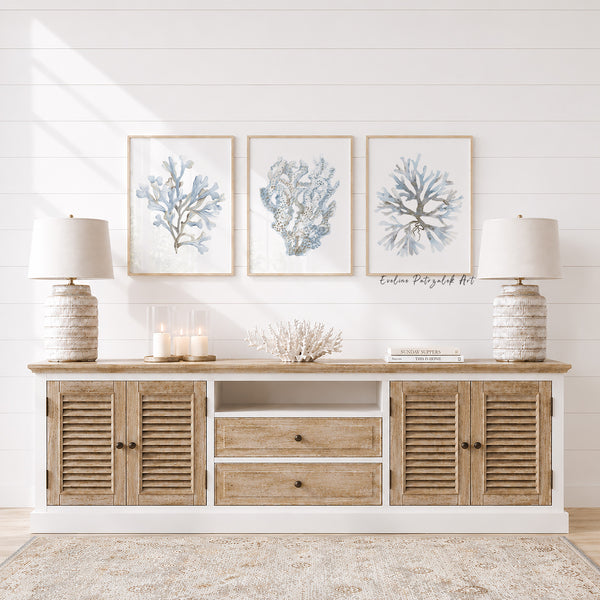 Wooden console table with decorative items and wall art with 3 coastal light blue corals  in a room with white walls.