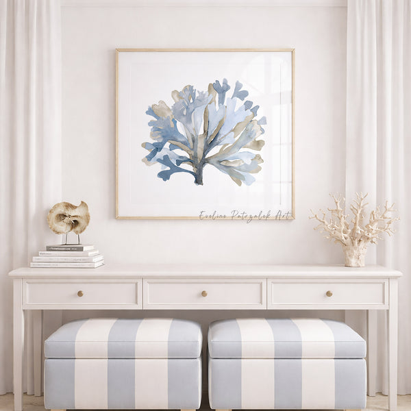Framed artwork of a coral on a wall above a white console table with striped ottomans.