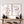 Two framed botanical wall art prints with red berries on branches, displayed above a wooden console table with dark vases and candles in a bright interior setting.