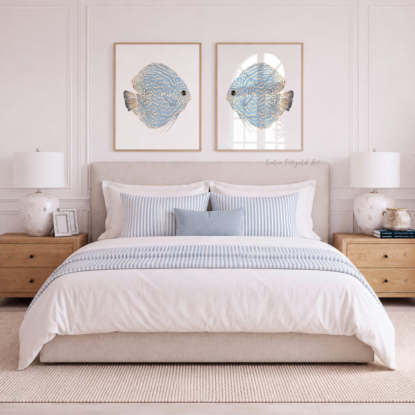 A styled bedroom scene with a bed dressed in white bedding and blue striped accents, flanked by matching nightstands and lamps, with two framed fish wall art prints above the headboard.