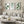 Watercolor paintings of various green tropical leaves add a touch of nature to a living room with a white sectional sofa, a round coffee table, and a floor lamp.