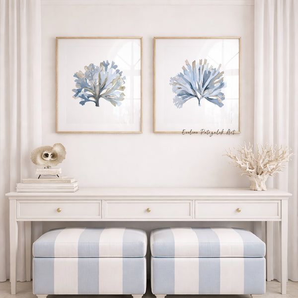 Framed artwork of blue coral on a white wall above a white console table with striped ottomans.