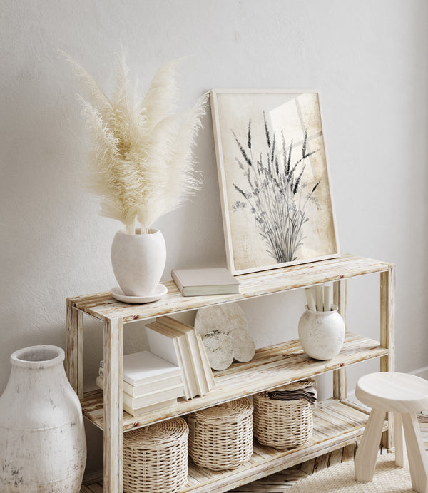 A close-up of a botanical illustration showcasing a bouquet of flowers in black ink on a vintage-inspired tan background. The artwork is displayed on a console table with pampas grass and other decorative elements.