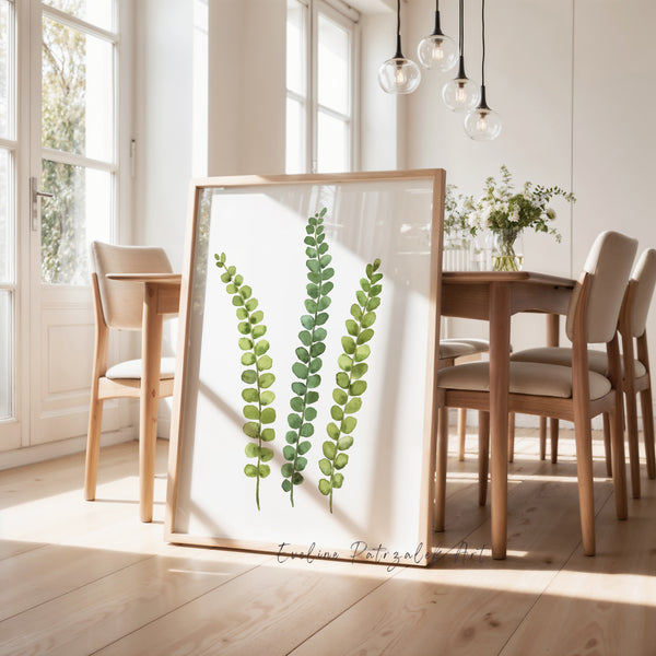Framed artwork of green leaves in a bright room with wooden furniture