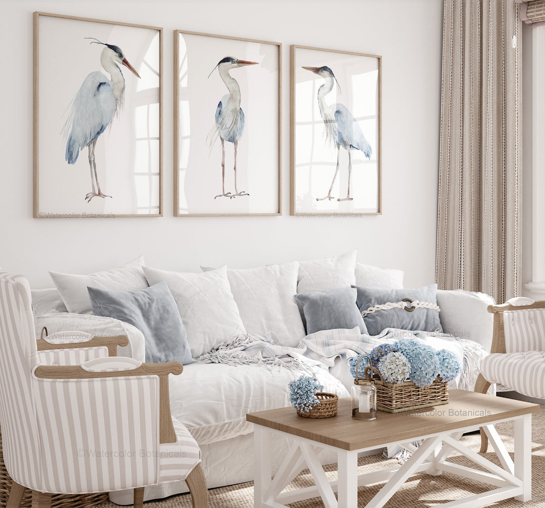 Living room with three heron paintings on the wall, a white sofa, and decorative items.