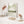A framed abstract landscape art print with soft green and beige tones, styled on a white console table with dried plants and neutral home decor accessories.