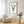 A framed watercolor painting showcases the intricate details of a fern, its small, soft green leaves rendered in subtle hues, adding a touch of nature to a living room with a plush armchair, a coffee table, and a vase of flowers.