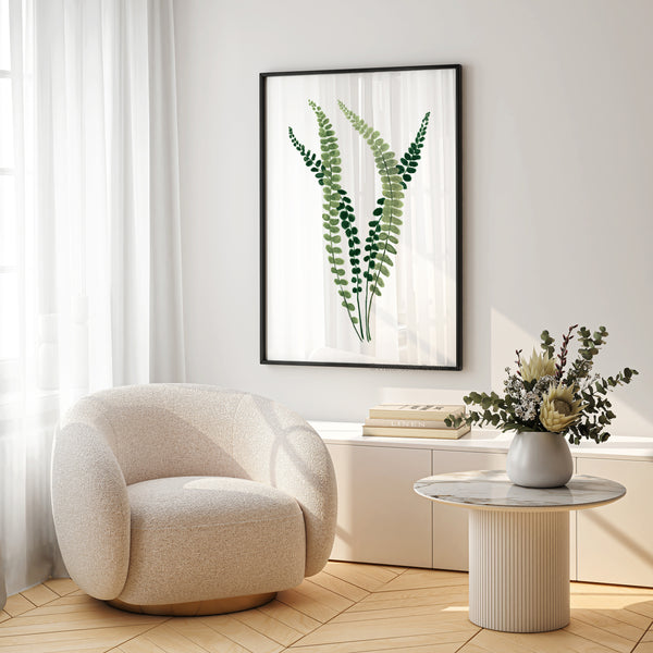A framed watercolor painting showcases the intricate details of a fern, its small, soft green leaves rendered in subtle hues, adding a touch of nature to a living room with a plush armchair, a coffee table, and a vase of flowers.