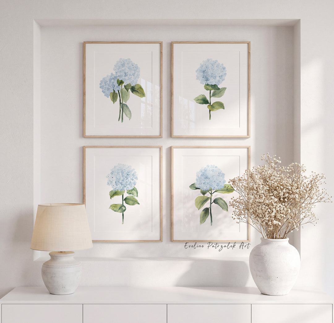 A set of 4 watercolor hydrangea prints featuring soft blue flowers, delicate green leaves, and individual botanical compositions on clean white backgrounds.
From fuller hydrangea clusters to simple single stems, the four prints create natural variation when displayed together in mat wooden frames. The generous white space keeps the artwork light and 
