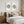 A styled bedroom scene with a wooden bed dressed in white bedding and accent pillows, flanked by matching bedside tables and lamps. Above the bed hang two framed wall art prints showing green patterned duscus fish on a white background.